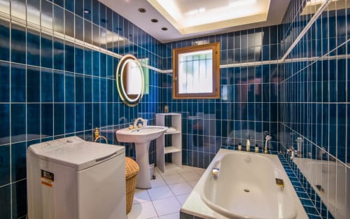 Baño moderno con azulejos azul oscuro, lavamanos pedestal, inodoro y bañera en la villa La Conciergerie en Millau