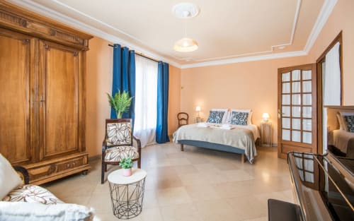 Dormitorio amplio en villa de Millau con armarios de madera, cortinas azules, cama queen y comodidades modernas