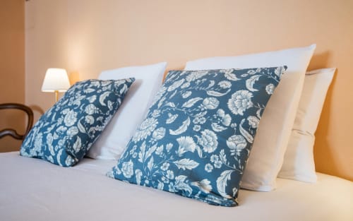 Dormitorio de lujo en La Conciergerie, Millau con almohadas florales azules y ropa de cama blanca