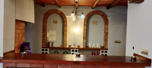 Barra del bar en Alojamientos Las Mellis en Antequera con nichos de ladrillo arqueado e iluminación decorativa