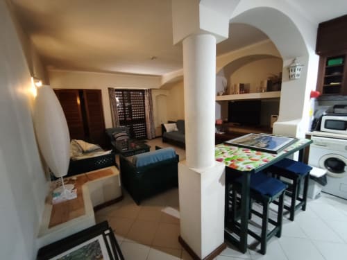 Área de estar integrada na Albufeira Inn com cozinha, mesa de jantar, sofá e arcos
