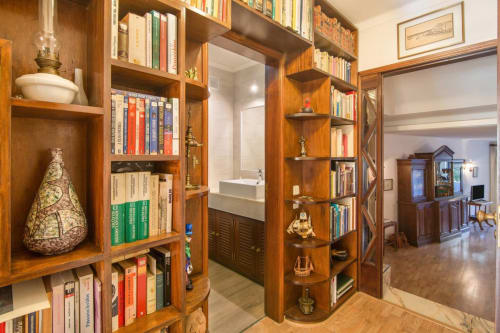 Estantes de madeira embutidas exibindo livros e artigos decorativos no corredor de entrada da suíte do Albufeira Inn