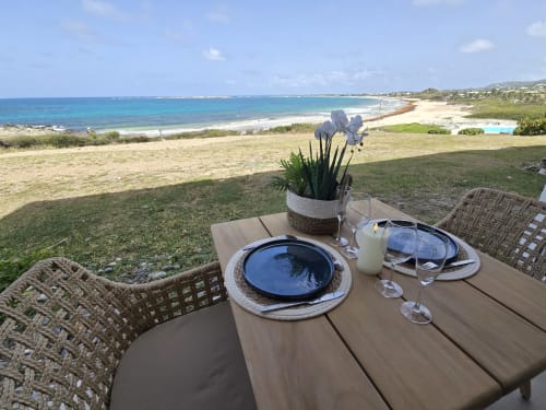 Table de salle à manger extérieure avec vue sur les eaux turquoise des Caraïbes, appartement Paradise Lagoon de Grimaud Locations à Cul-de-Sac