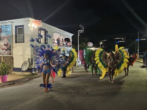 Défilé de carnaval coloré avec danseuses en plumes dans des costumes vibrants la nuit à Cul-de-Sac, St-Martin