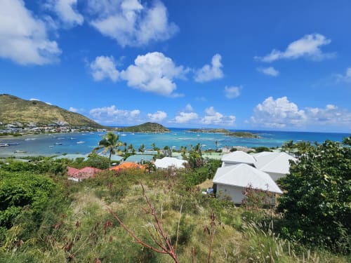 Vue tropicale de la baie de Cul-de-Sac avec immeuble aux toits blancs, voiliers et palmiers sous ciel bleu