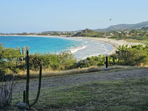 Vue sur la baie turquoise depuis l'appartement Paradise Lagoon à Cul-de-Sac avec plage de sable, collines et végétation tropicale