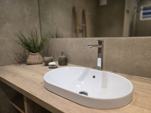 Évier ovale blanc moderne avec robinet haut sur meuble en bois dans la salle de bains de l'appartement Paradise Lagoon à Grimaud Locations