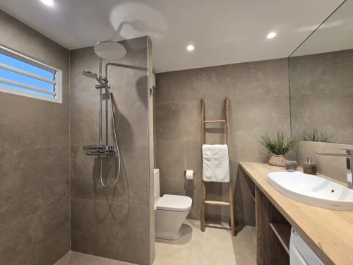 Salle de bains moderne à l'appartement Paradise Lagoon à Grimaud, avec douche à l'italienne, lavabo blanc et porte-serviettes en bois