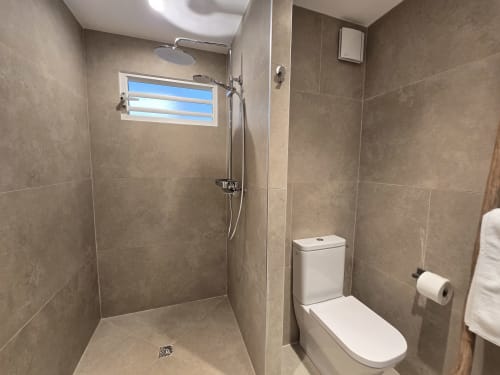 Salle de bain moderne avec douche à l'italienne, toilettes et fenêtre à l'appartement Grimaud Locations Paradise Lagoon à Cul-de-Sac