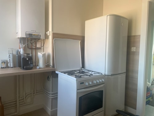 Cuisine moderne de l'appartement à Gérardmer avec cuisinière à gaz, réfrigérateur et petits appareils sur le plan de travail