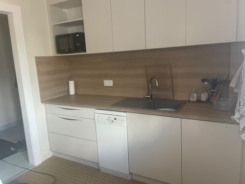 Cuisine moderne avec armoires blanches, plan de travail en bois, électroménagers intégrés et dosseret à Gérardmer.