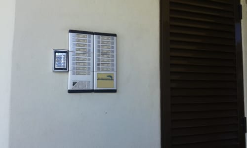 Sistema de intercomunicação com teclado e botões de porta instalados na parede branca na entrada do edifício do apartamento Albufeira Inn
