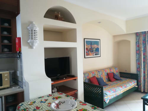 Apartamento estúdio luminoso em Albufeira Inn com nicho para TV, sofá com padrões coloridos, kitchenete e vista para a cidade