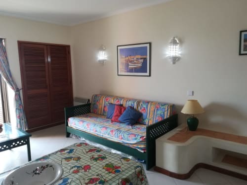 Estúdio colorido no Albufeira Inn com cama-divã estampada, almofadas decorativas, arandelas de parede e arte náutica
