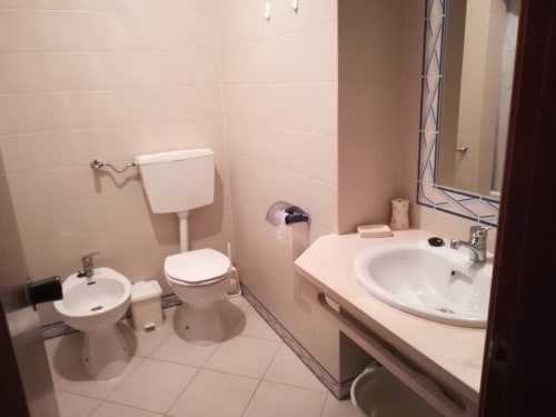 Casa de banho moderna no Albufeira Inn com duas pias, sanita, bidé e pavimento em azulejos no apartamento Bellavista Ténis Clube