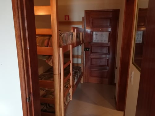 Corredor do apartamento Albufeira Inn com beliches, portas de madeira e piso em azulejo