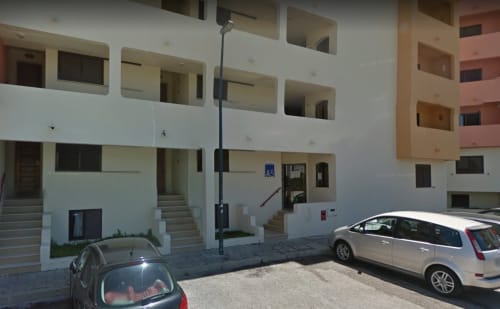 Fachada branca do apartamento Albufeira Inn com carros estacionados e múltiplas varandas em Portugal