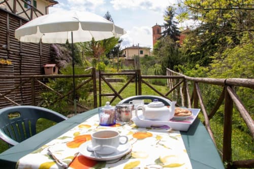 Outdoor dining area at Casa di Cinti in Loiano with tea service, pastries, and garden views of the Tuscan countryside.