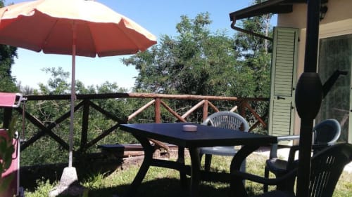 Outdoor dining area at Casa di Cinti with black table, red umbrella, and mountain views in Loiano, Italy