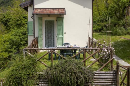 Rustic wooden deck with garden seating at Casa di Cinti apartment in Loiano, surrounded by lush greenery