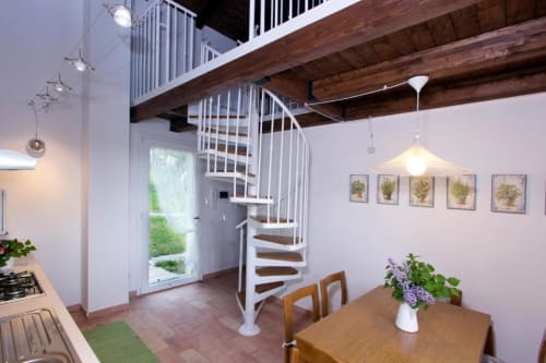 Modern two-level apartment at Casa di Cinti with spiral staircase, wooden beams, dining table, and garden view in Loiano,