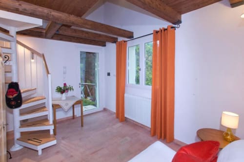 Bright modern apartment at Casa di Cinti with wooden beams, orange curtains, white walls, wooden flooring, stairs, and garden