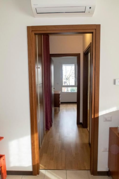 Wooden framed doorway opening to hallway with hardwood floors at Casa di Cinti apartment, Pianoro