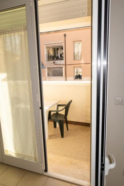 Balcony door opening to inner courtyard at Casa di Cinti, Pianoro. Black chair on terracotta tile floor with peach building