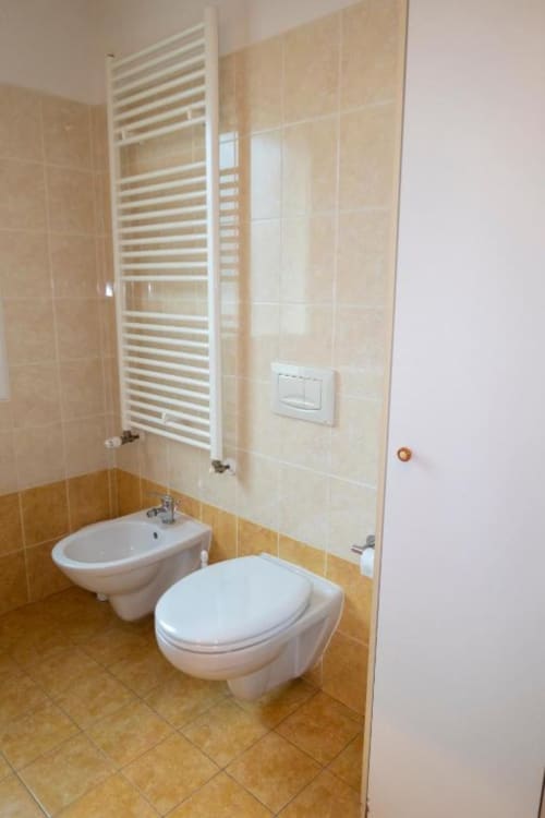 Modern bathroom in Esperanto apartment at Casa di Cinti B&B, Pianoro, with toilet, bidet, towel rack and beige tile walls