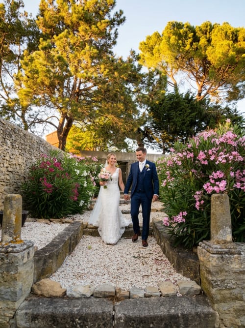 Recién casados caminando de la mano por el romántico jardín del Domaine De Poulharies en Carcasona