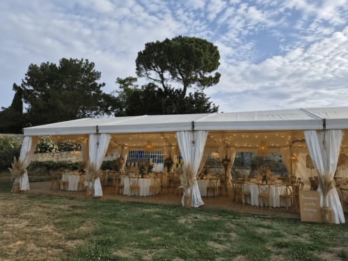 Elegante carpa de boda al aire libre en el Domaine De Poulharies en Carcasona con luces de cuerda, cortinas blancas y mesas decoradas