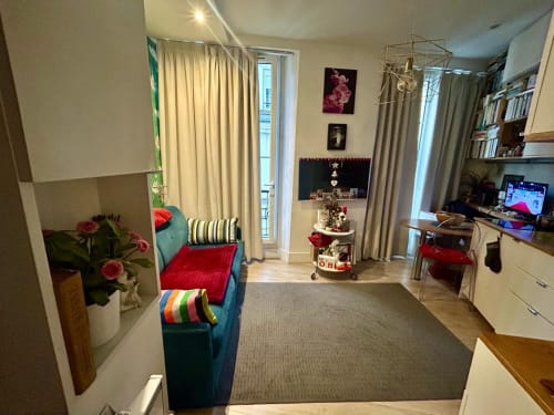 Cocoon Gallery Paris studio deluxe with city view, blue sofa, red cushions, flowers, desk with TV, and open balcony door
