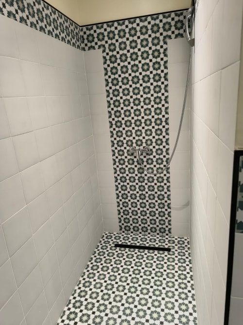 Modern shower stall in SAMYAflat apartment, Tangier, with white subway tiles and patterned green geometric floor design