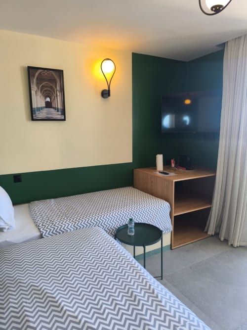 Modern hotel room at SAMYAflat Tangier with twin beds, green accent wall, TV, and contemporary furnishings