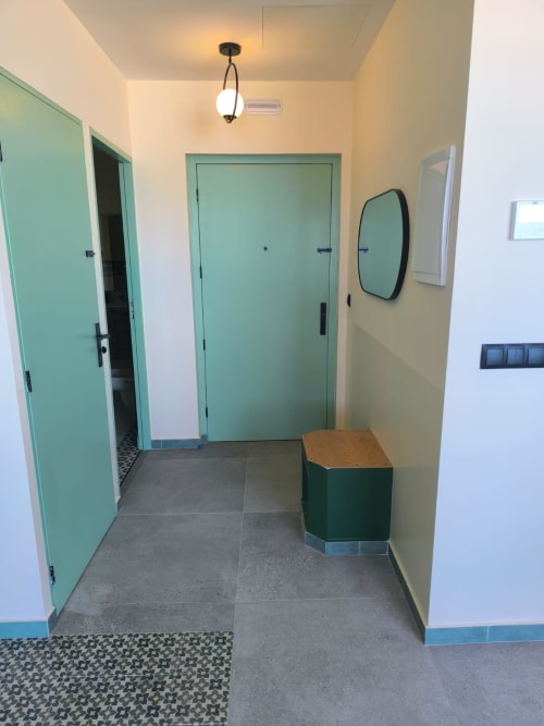 Modern hallway at SAMYAflat apartment in Tangier with turquoise doors, pendant lighting, and black-framed mirror
