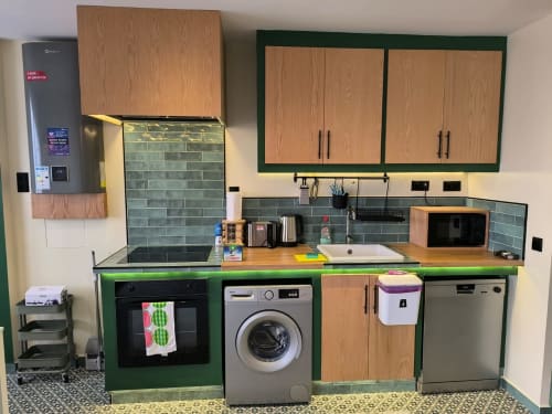 Modern green kitchen at SAMYAflat Tanger apartment with wood cabinets, stainless appliances, and teal backtile