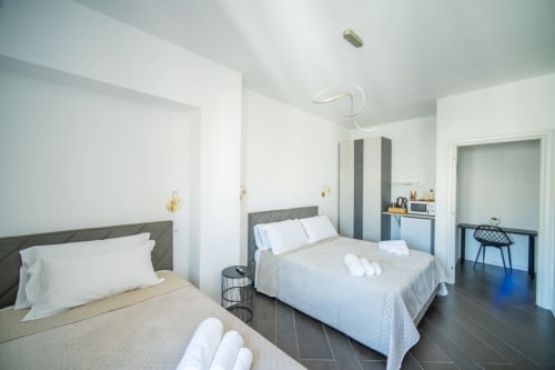 Camera da letto matrimoniale moderna dell'hotel Newhouse a Bari con testiere grigie, biancheria bianca e illuminazione contemporanea