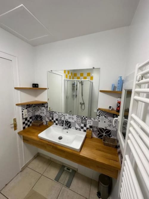 Salle de bain moderne à la Villa des Palmiers avec meuble-lavabo en bois, carrelage à motifs et douche spacieuse