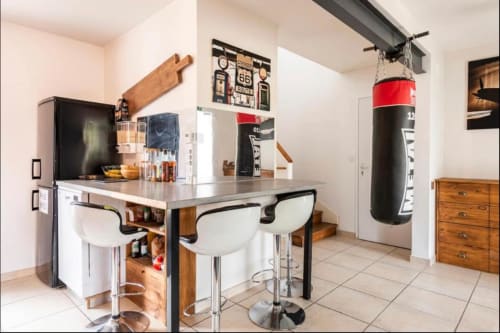 Espace moderne de cuisine-bar à la Villa des Palmiers B&B avec bar, sac de boxe et décoration sportive à Villeneuve-sur-Lot