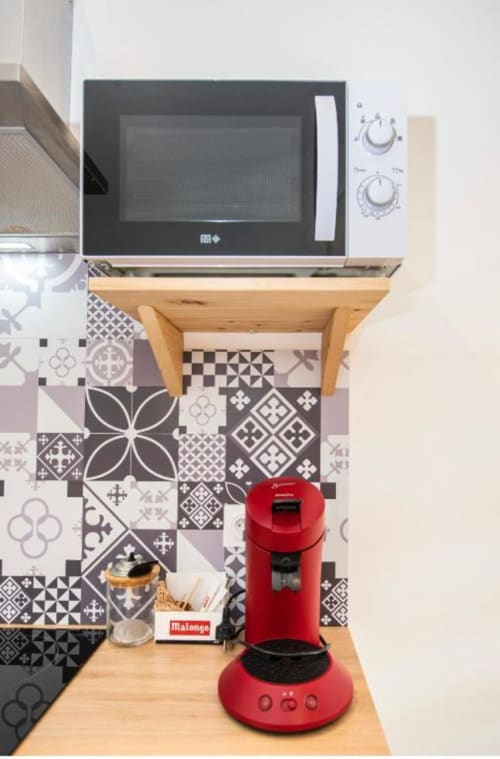 Kitchenette du studio à la Villa des Palmiers avec micro-ondes, cafetière rouge, dosseret à motifs et comptoir en bois