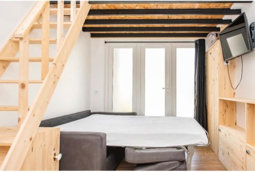 Chambre moderne à la Villa des Palmiers avec poutres en bois, lit, télévision et portes vitrées donnant sur la terrasse