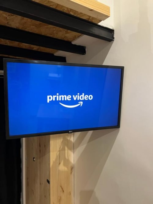 Téléviseur LG écran plat fixé sur mur en bois affichant le logo Prime Video dans la suite Villa des Palmiers