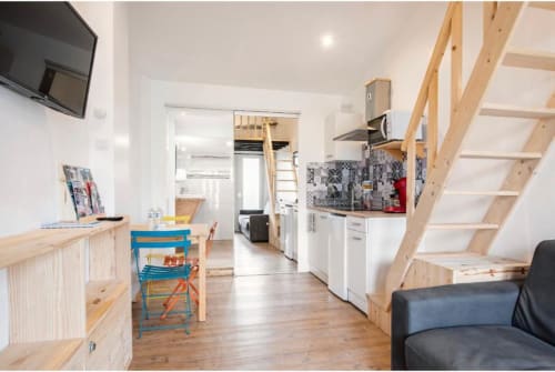 Studio à la Villa des Palmiers à Villeneuve-sur-Lot avec escalier mezzanine en bois, kitchenette, coin repas et TV écran plat