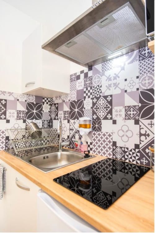 Cuisine moderne à la Villa des Palmiers avec carrelage rétro noir et blanc, comptoir en bois, évier inox