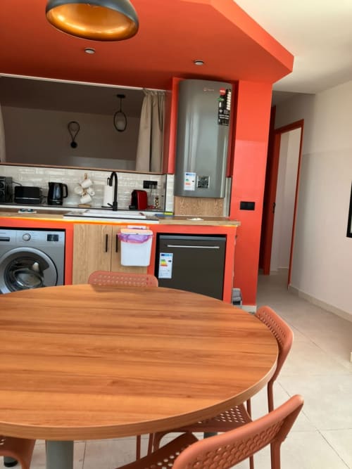 Modern kitchen-dining area in YaYaCaSa Ocre apartment at SAMYAflat, Tanger with orange accents and wooden table