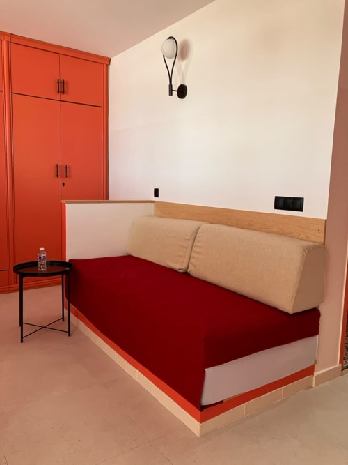 Modern bedroom at SAMYAflat Tangier with red platform bed, cream pillows, wood headboard, red wardrobe cabinet