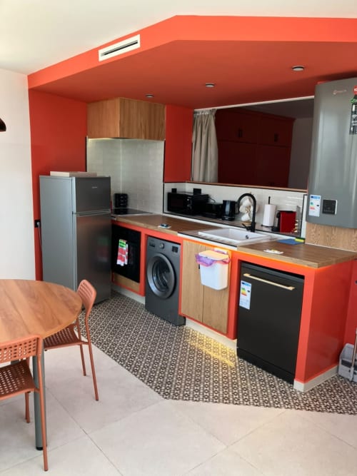 Modern red kitchen with stainless appliances, dining area, and washing machine at SAMYAflat apartment, Tanger