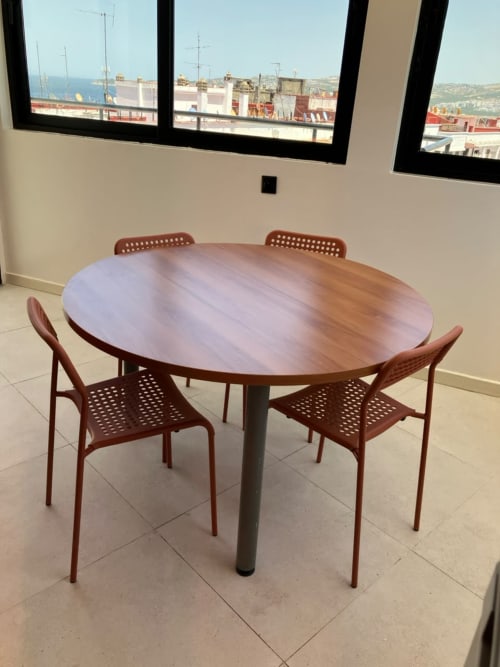 Modern dining area in YaYaCaSa Ocre apartment at SAMYAflat, Tangier with round wood table, red chairs, and sea view through