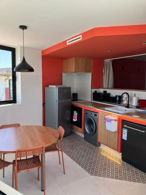 Modern kitchen-dining area at YaYaCaSa Ocre apartment in SAMYAflat, Tangier with red accents and black appliances