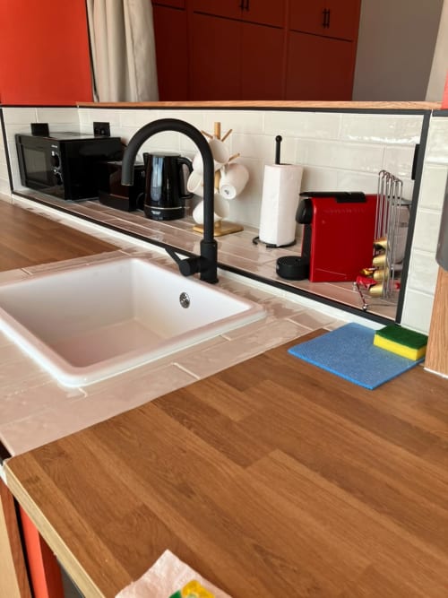 Modern kitchen sink with black faucet, white subway tile backsplash, and mirror at SAMYAflat apartment in Tangier